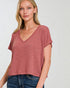Woman wearing a maroon t-shirt and blue jeans on a white background
