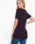 A woman wearing a black short-sleeve tunic top and blue jeans, photographed from the back against a clean white studio background.