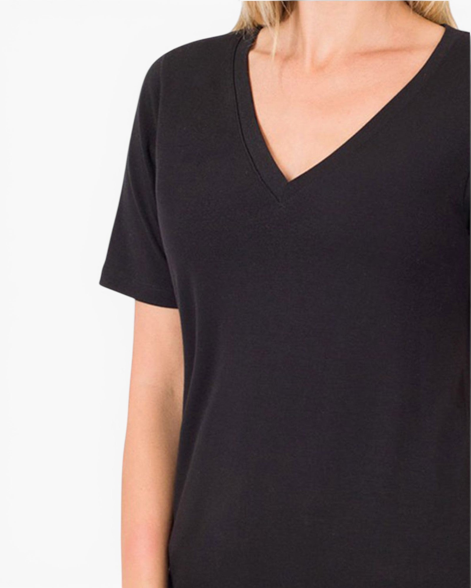 A close-up of a person wearing a plain black short-sleeve V-neck top against a light gray studio background.