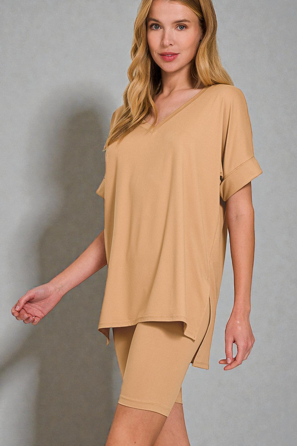 Woman wearing a beige outfit against a gray background