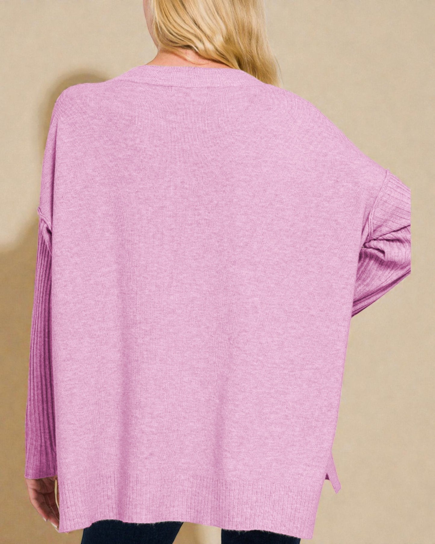 Pink cardigan worn by a person on a beige background