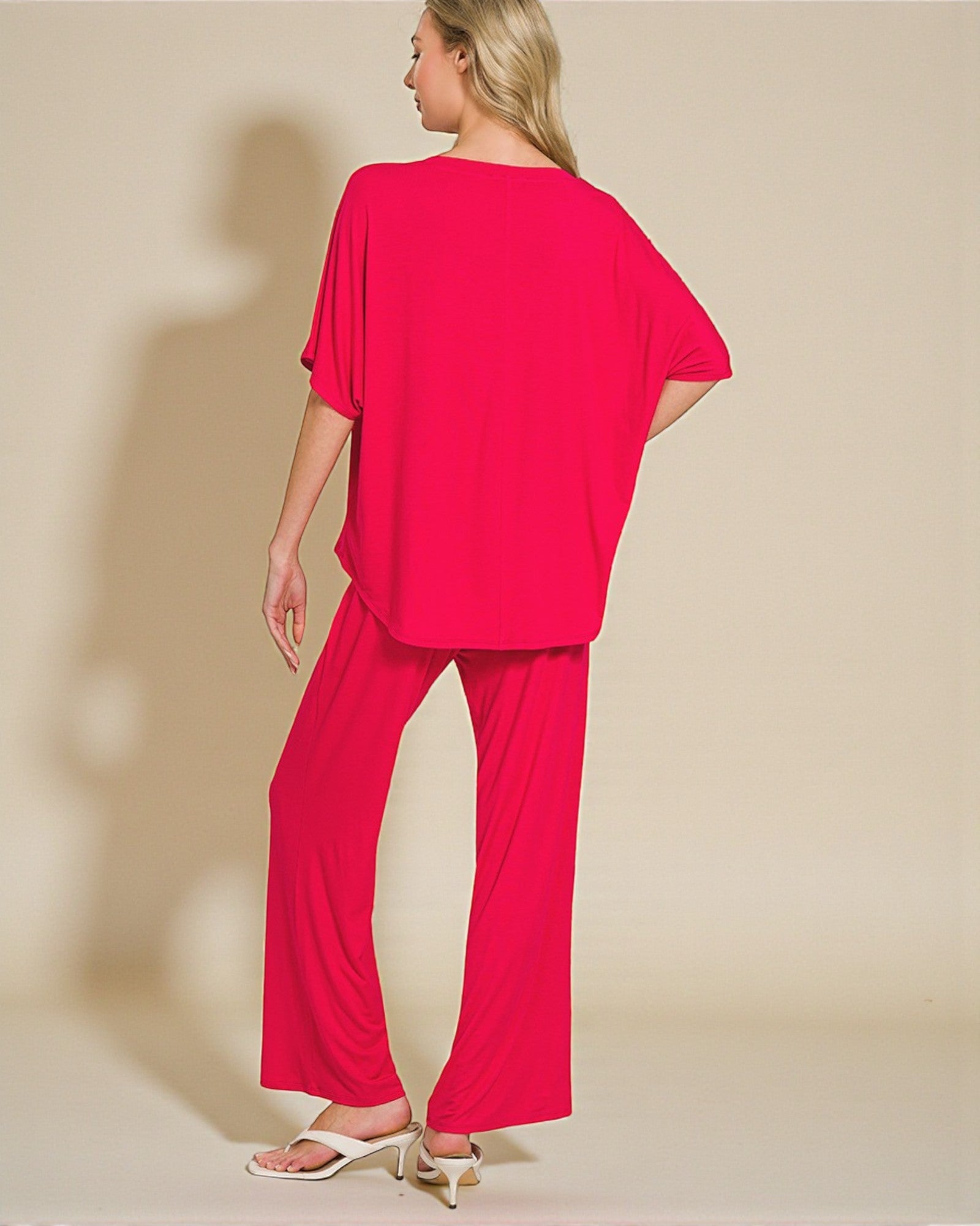 Woman wearing a bright pink outfit on a beige background