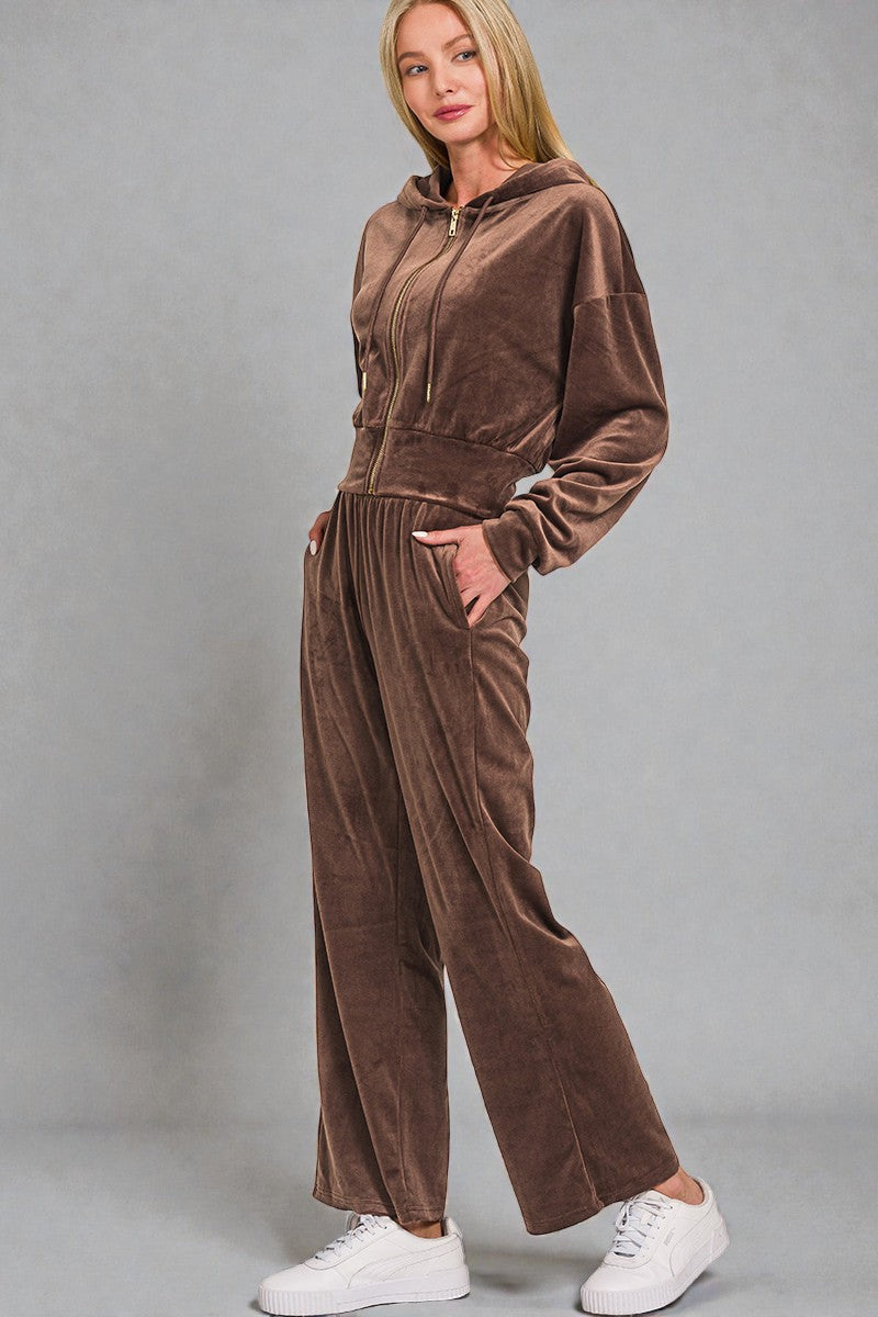 Woman wearing a brown velour tracksuit against a gray background