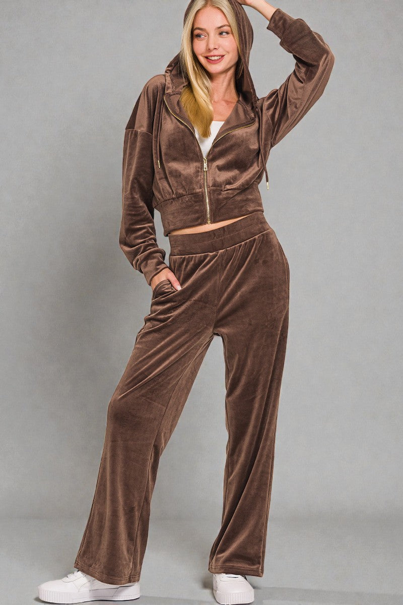 Woman wearing a brown velour tracksuit against a gray background