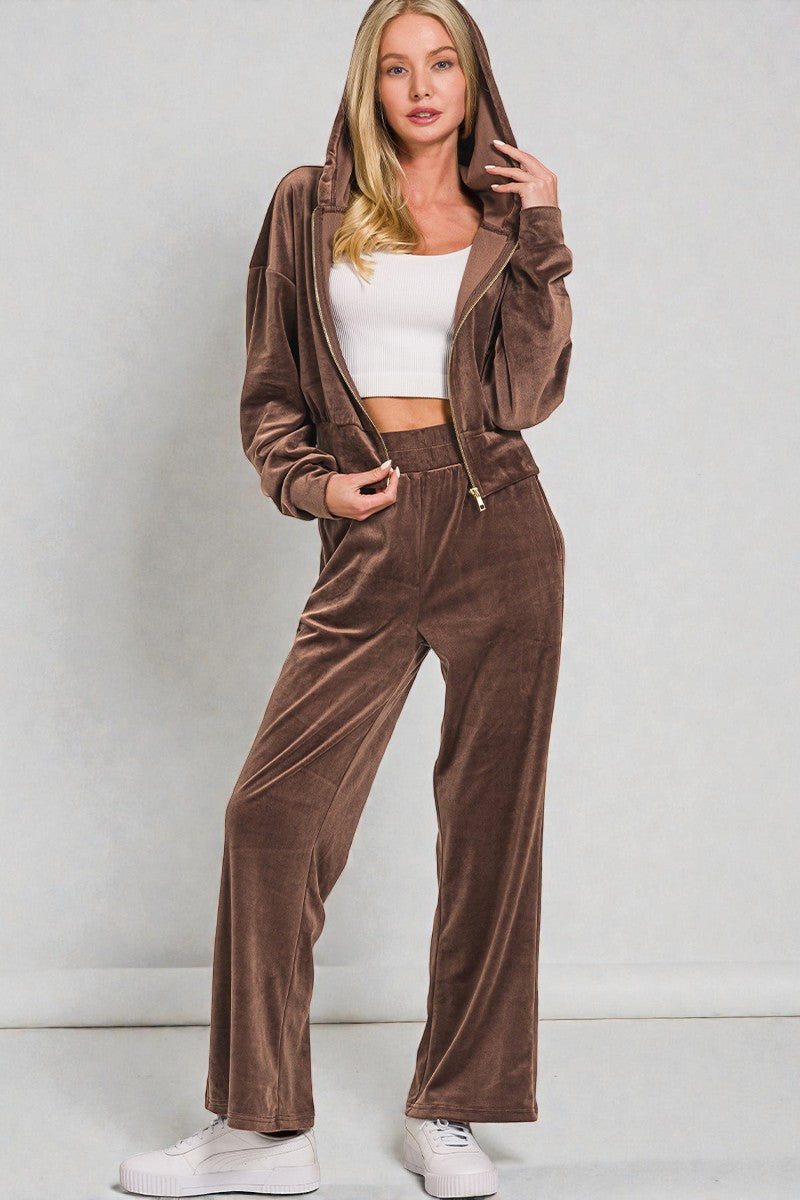 Woman wearing a brown velour tracksuit against a plain background