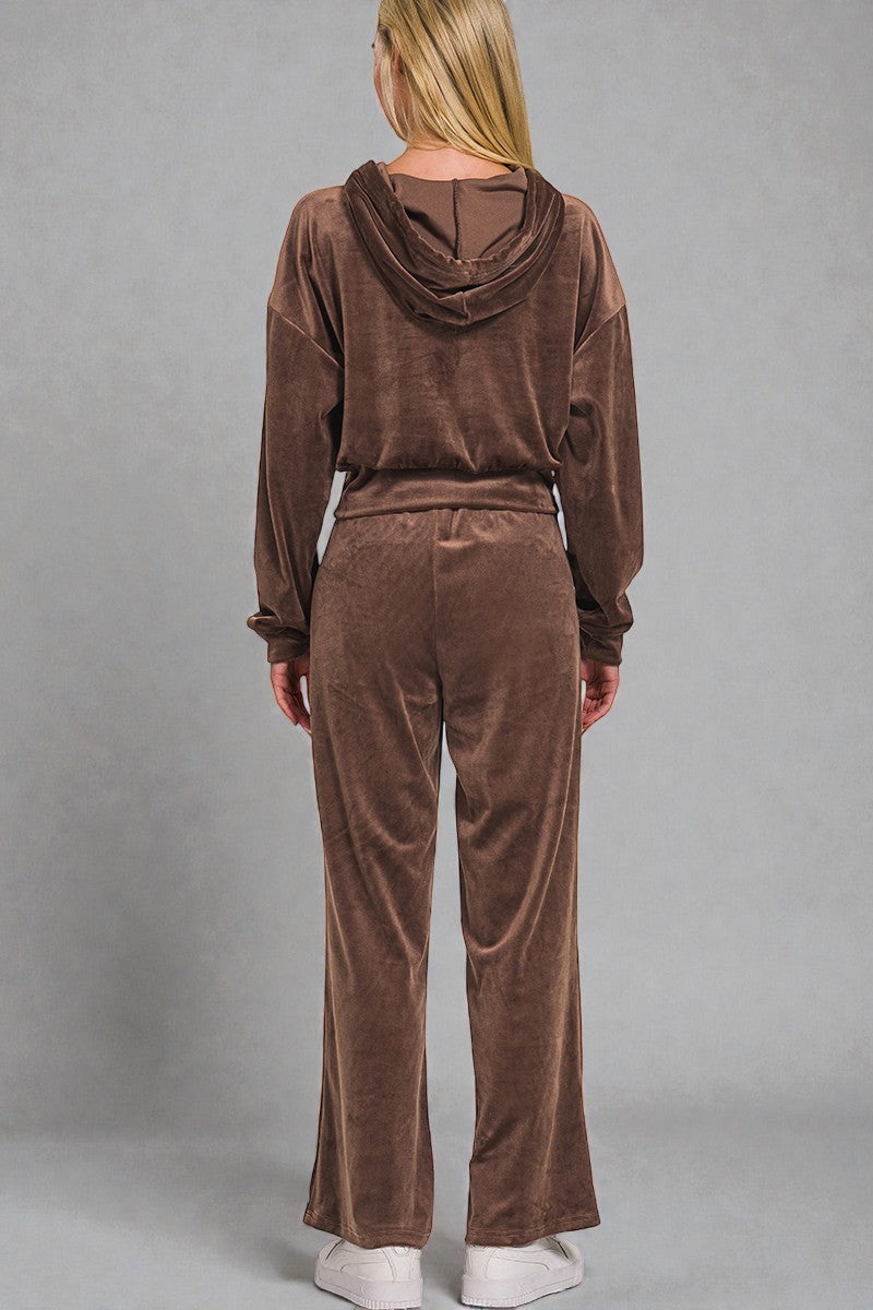 Person wearing a brown velour tracksuit against a gray background