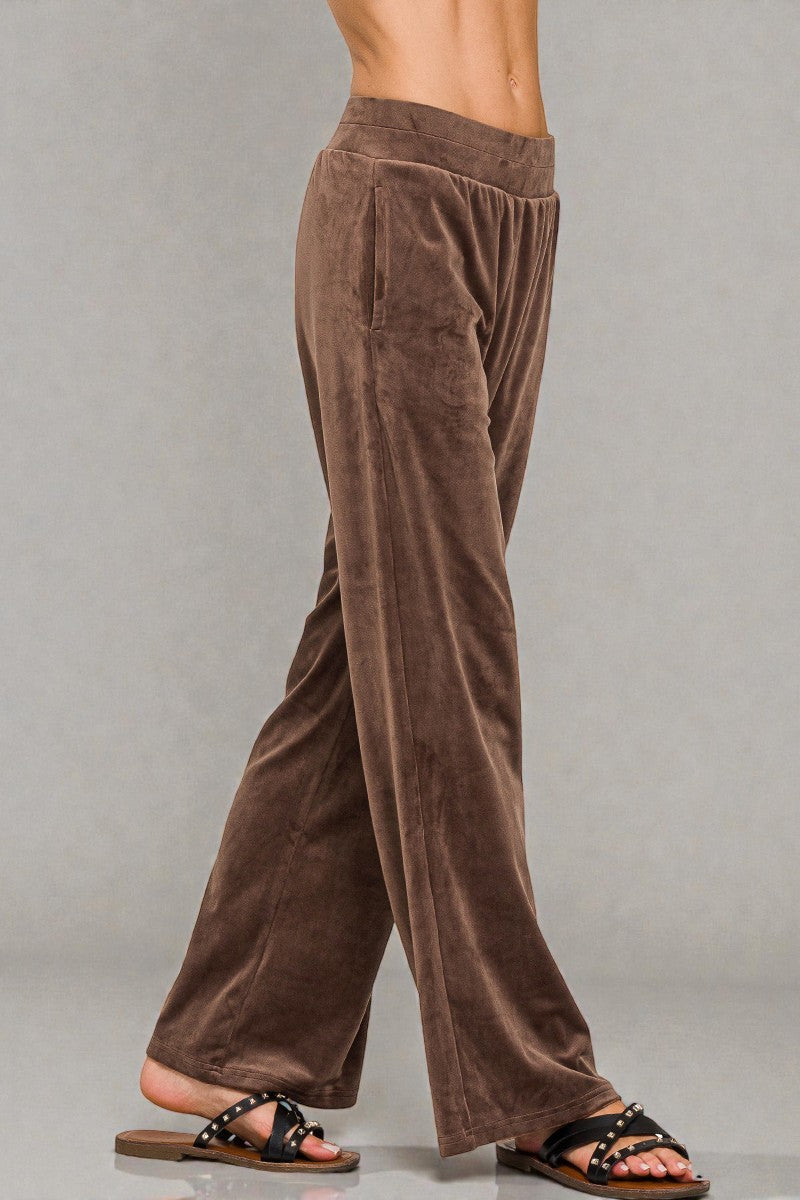 Brown velvet pants worn by a person on a gray background