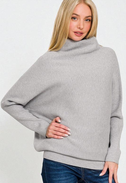 Woman wearing a gray sweater and blue jeans on a white background