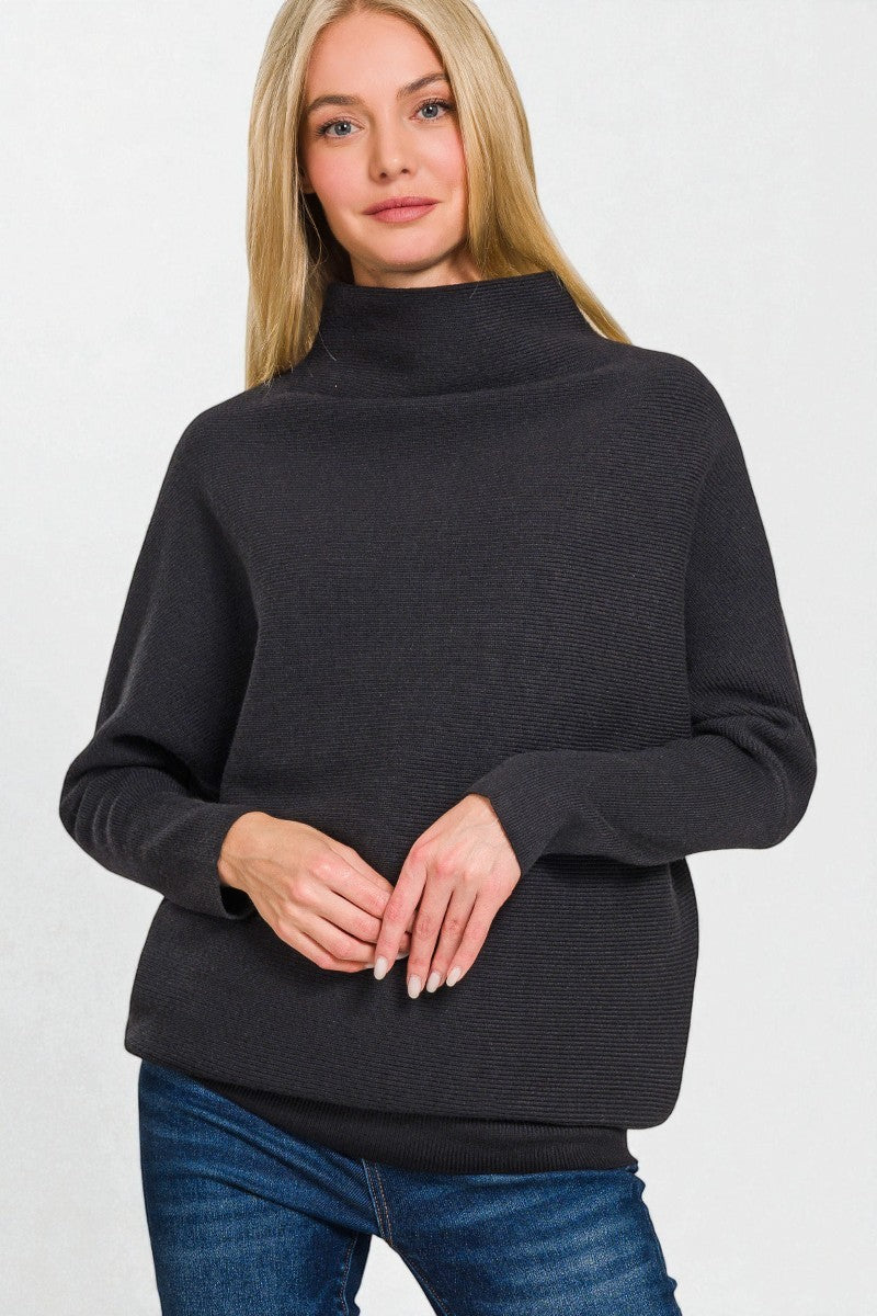 Woman wearing a black sweater and blue jeans on a white background