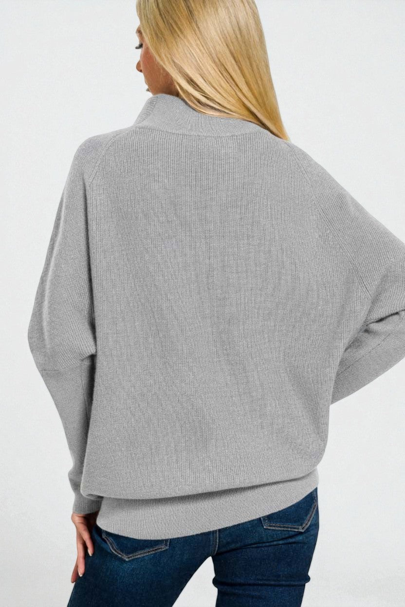 Person wearing a gray sweater and blue jeans on a white background