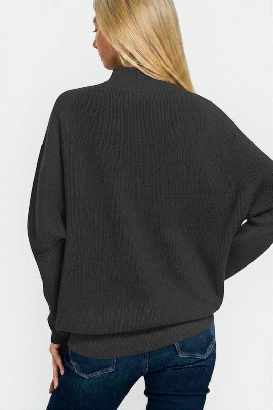 Person wearing a black sweater and blue jeans on a white background
