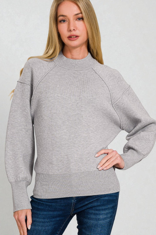 Woman wearing a gray sweater and blue jeans on a light gray background