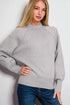 Woman wearing a gray sweatshirt and blue jeans against a white background