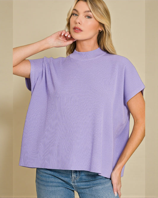 Woman wearing a purple top and blue jeans against a beige background