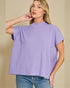Woman wearing a purple top and blue jeans against a beige background