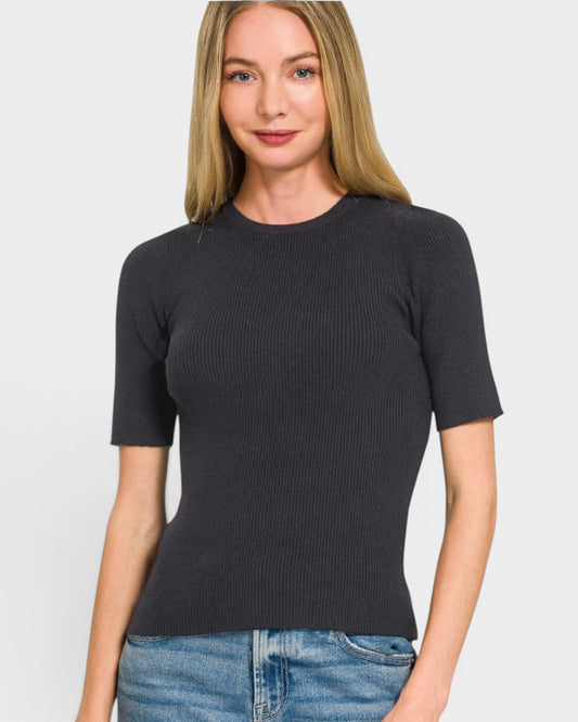 Woman wearing a black ribbed sweater and blue jeans on a white background