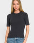Woman wearing a black ribbed sweater and blue jeans on a white background
