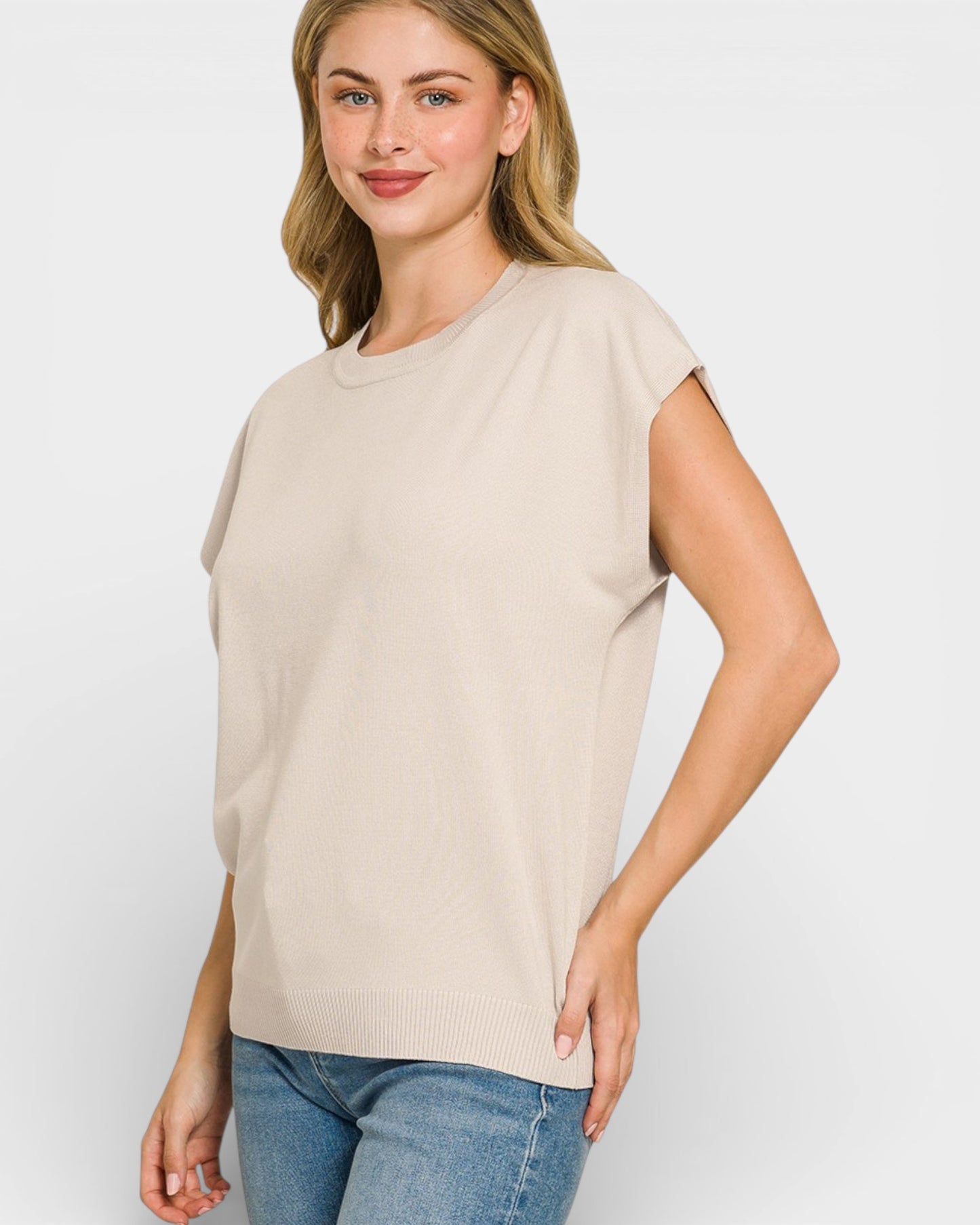 Woman wearing a beige t-shirt and blue jeans on a white background