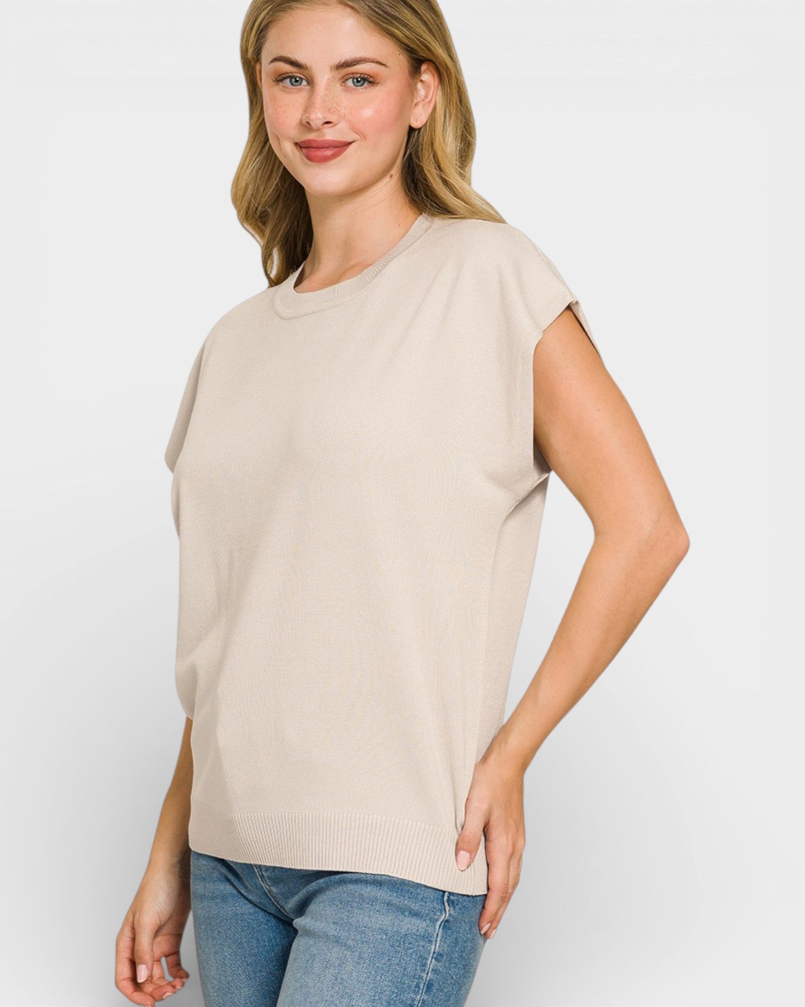 Woman wearing a beige t-shirt and blue jeans on a white background