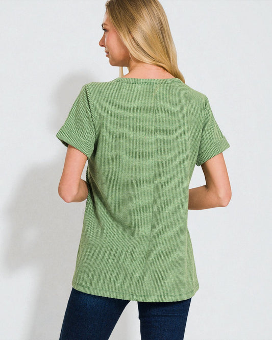 Woman wearing a green textured t-shirt against a white background