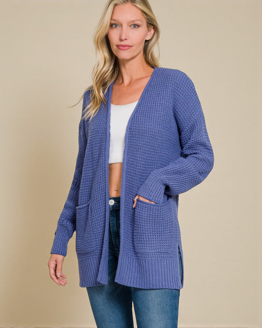 Woman wearing a blue cardigan over a white top and jeans on a beige background