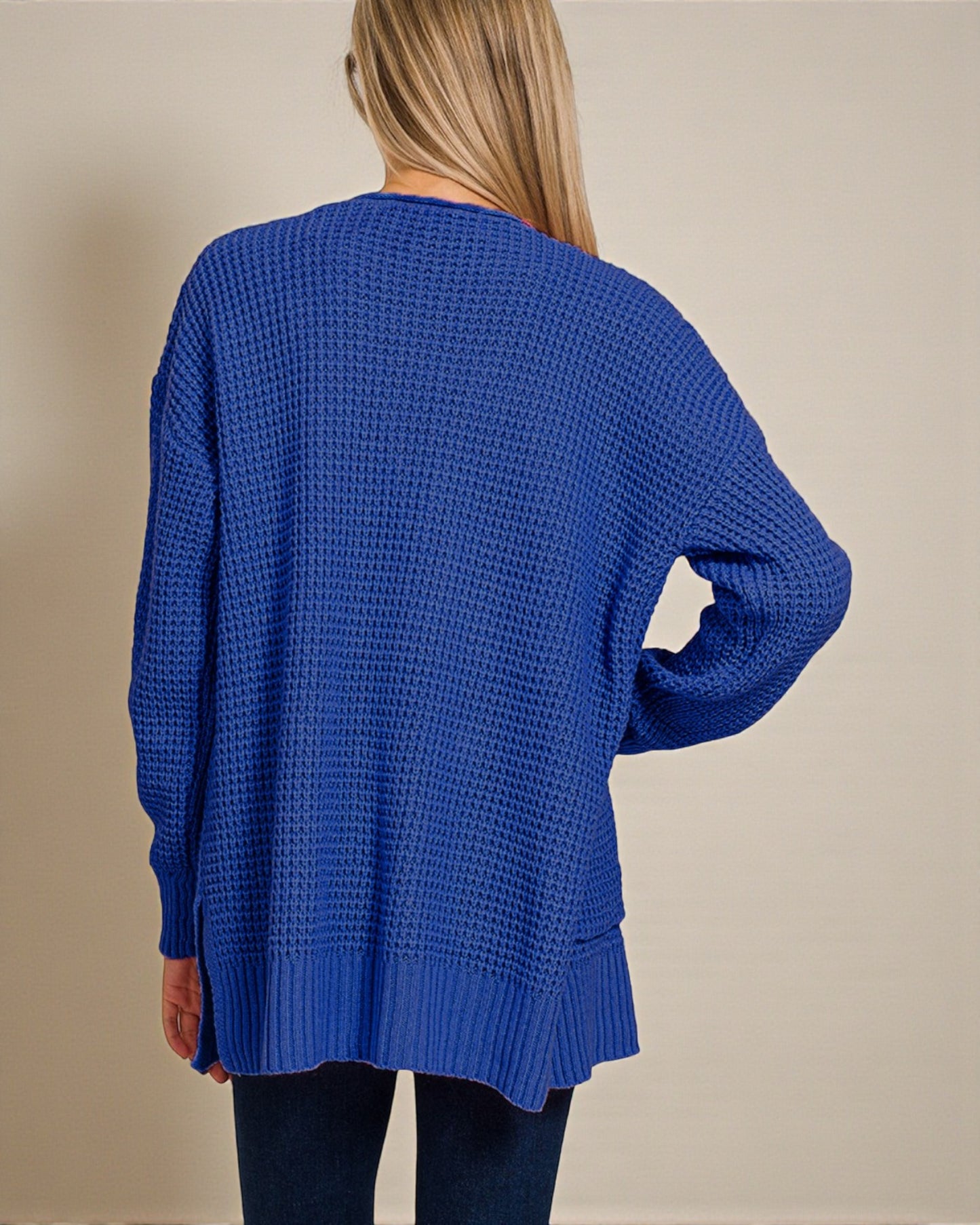 Blue knitted sweater worn by a person on a beige background
