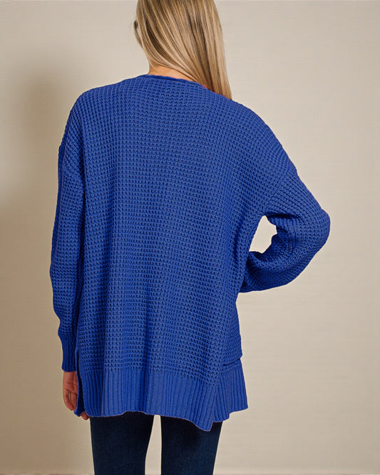 Blue knitted sweater worn by a person on a beige background