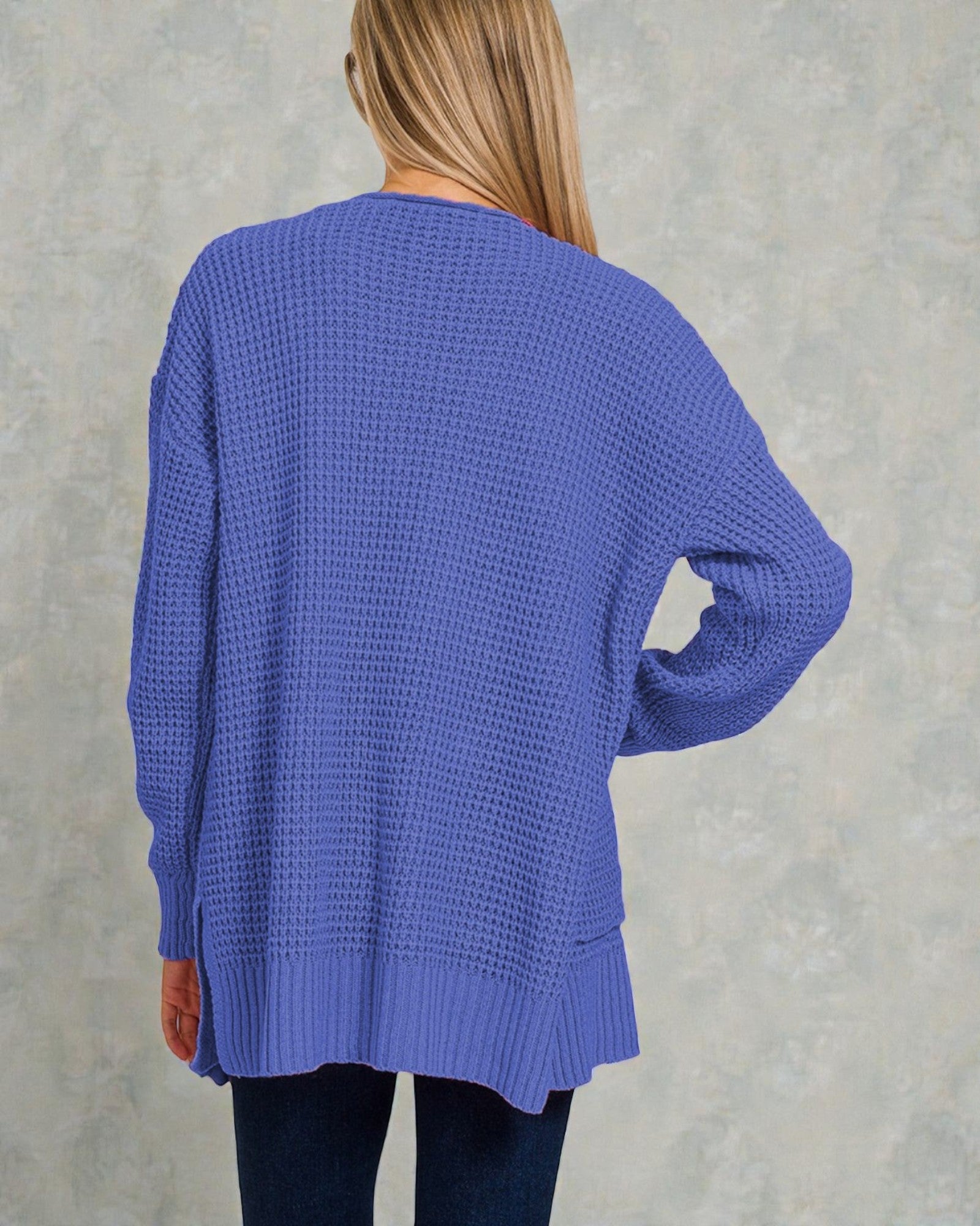 Person wearing a blue sweater against a gray background