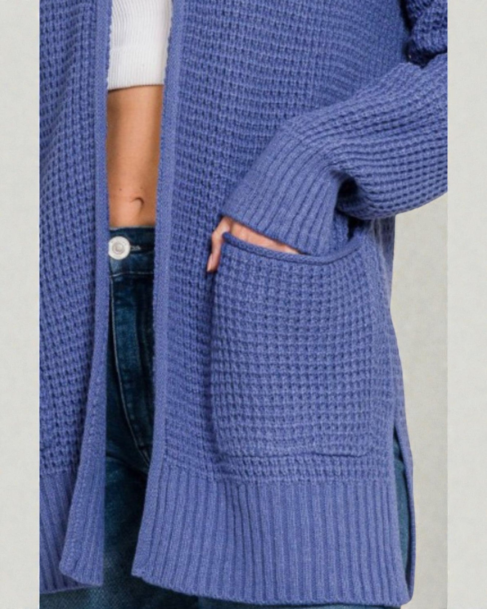 Blue knitted cardigan worn by a person on a light gray background