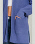 Blue knitted cardigan worn by a person on a light gray background