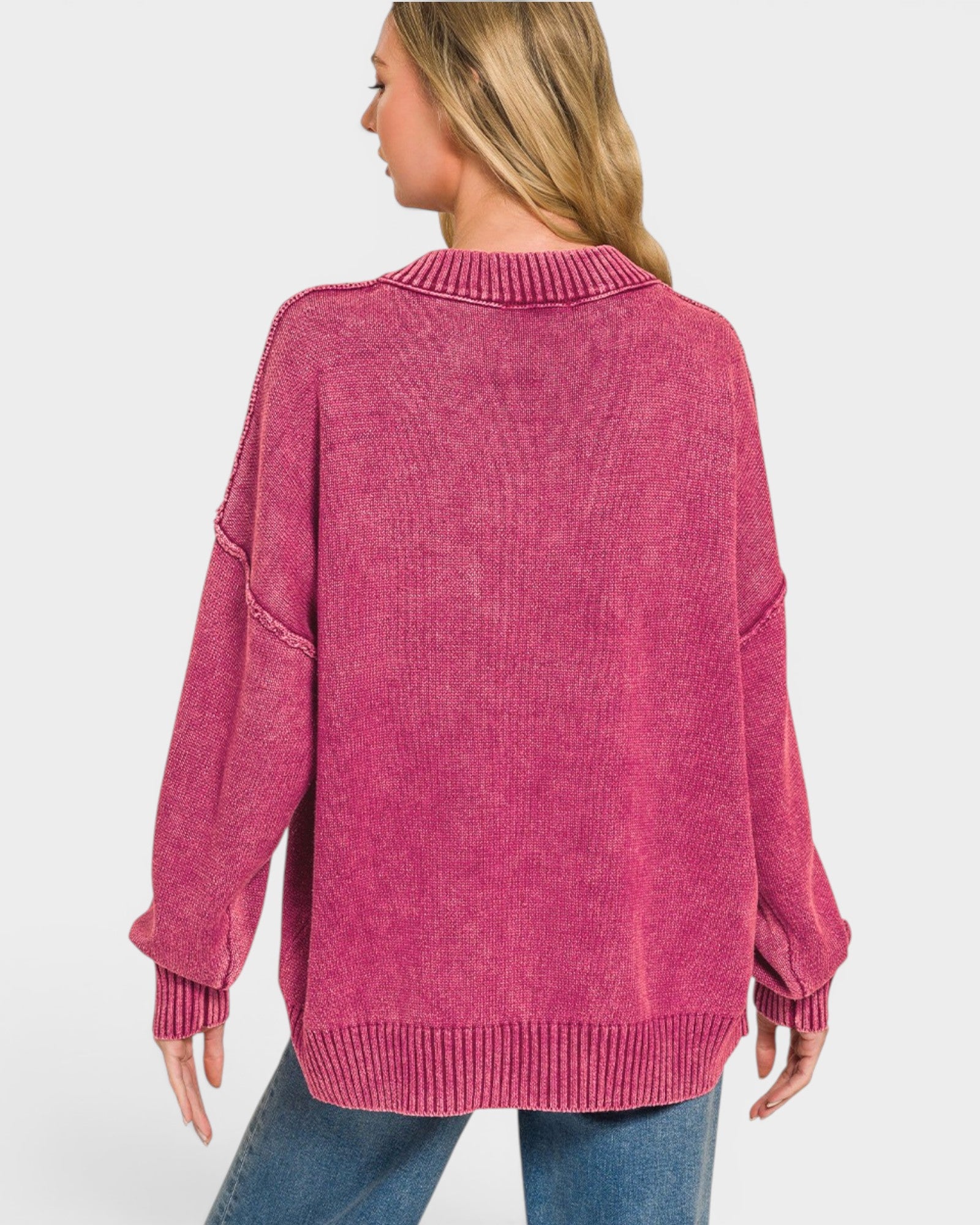 Person wearing a pink sweater on a plain background