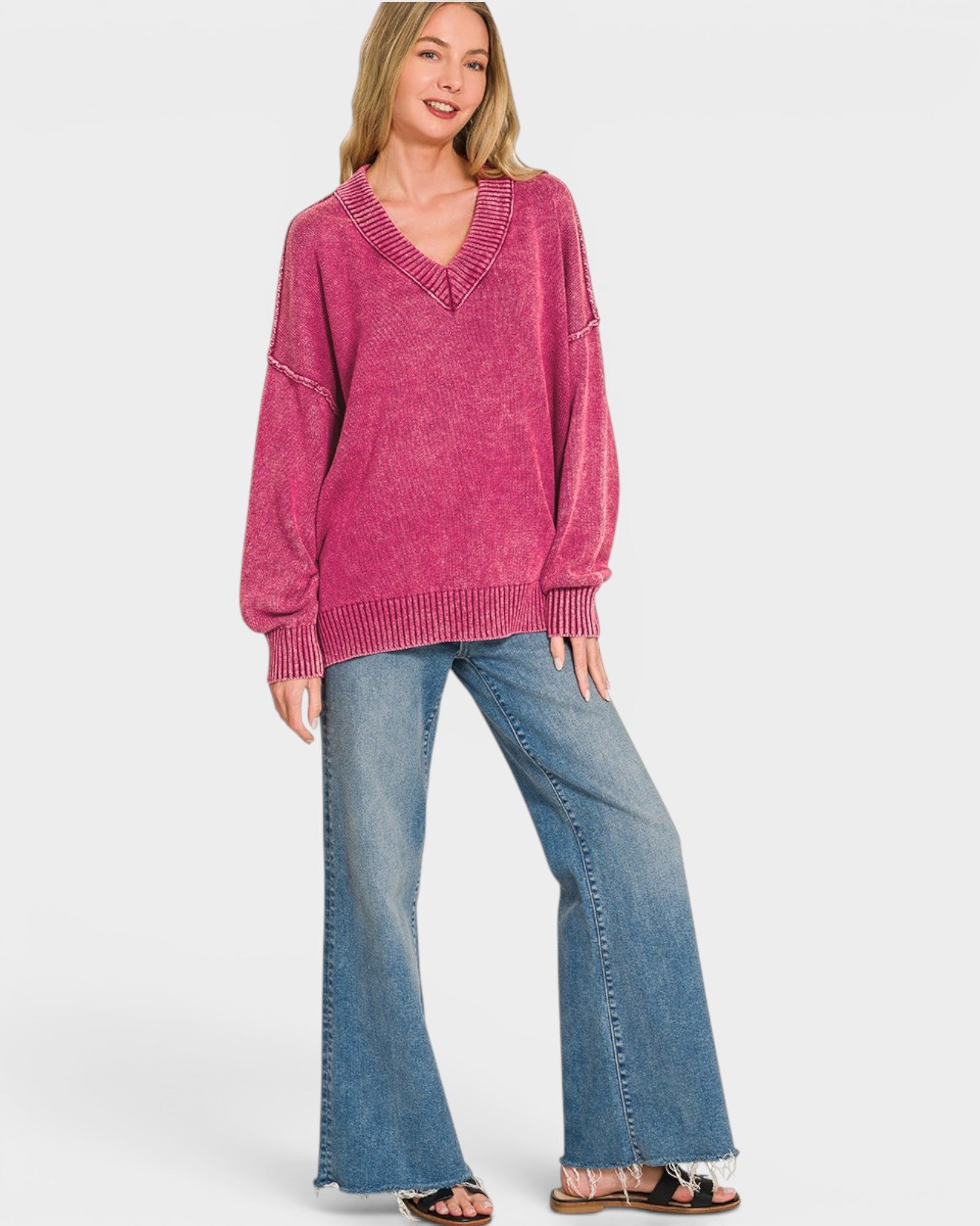 Woman wearing a pink sweater and blue jeans on a white background