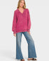 Woman wearing a pink sweater and blue jeans on a white background