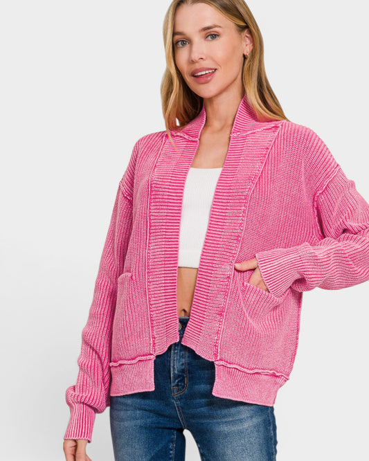 Woman wearing a pink cardigan over a white top and blue jeans on a white background