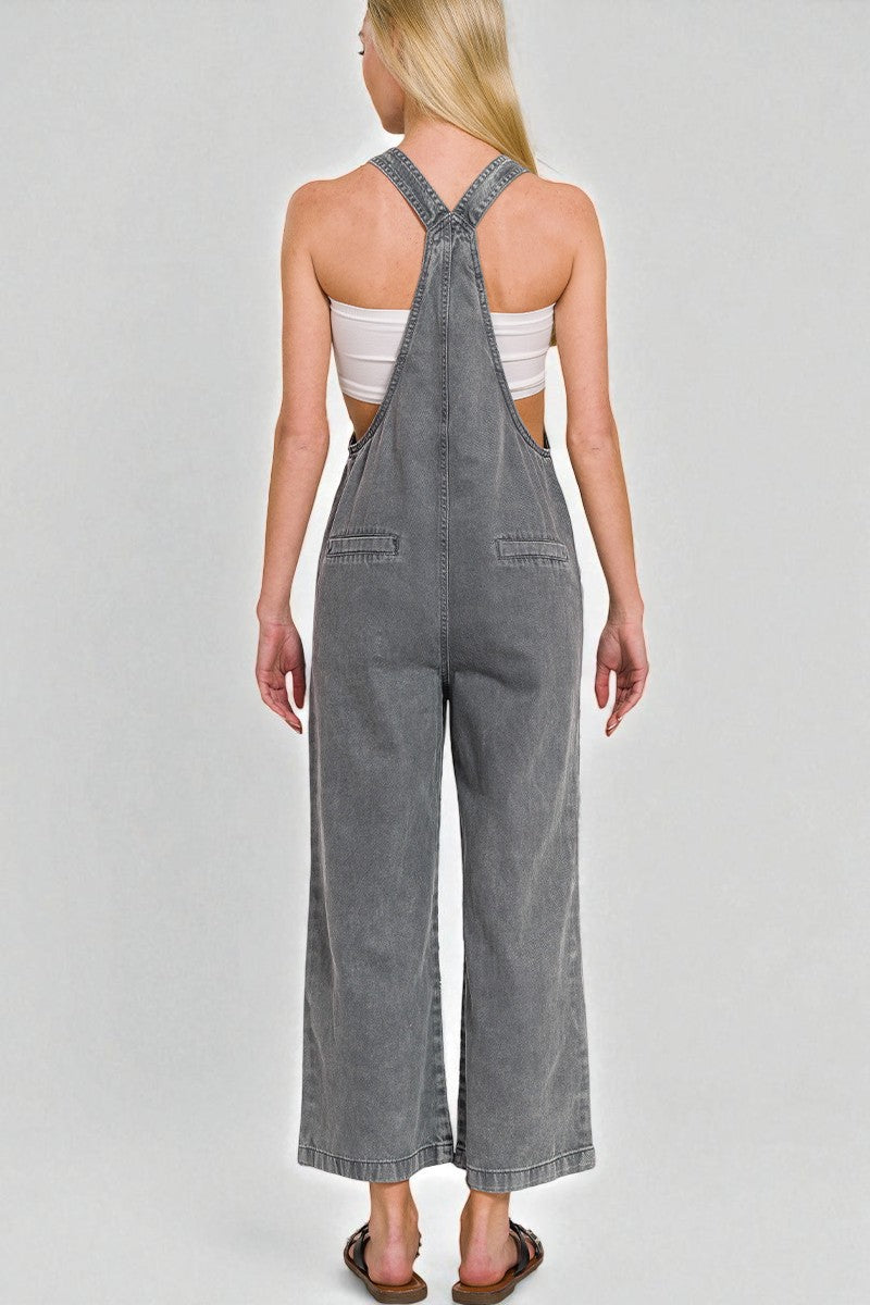 Person wearing gray denim overalls on a plain background