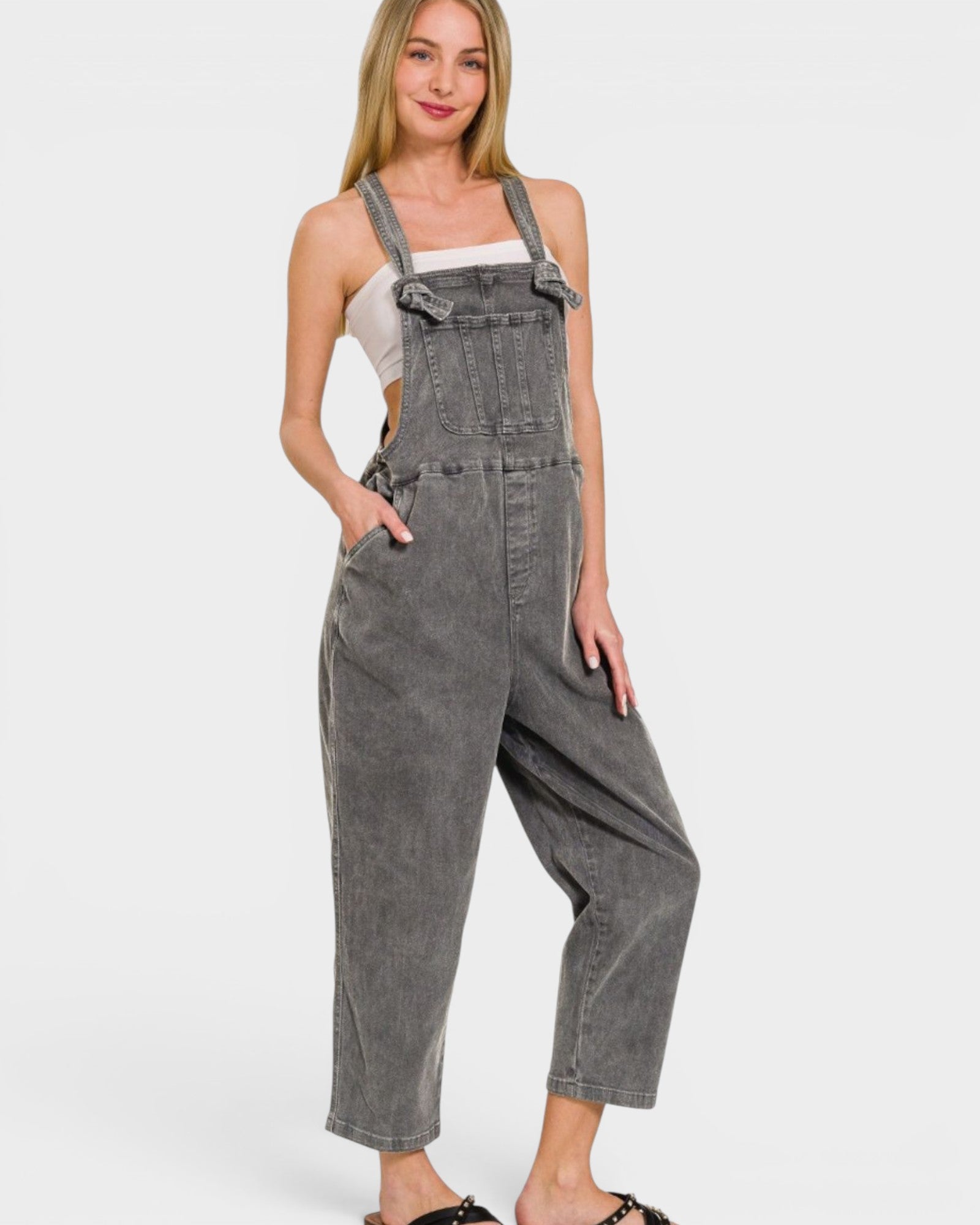 Woman wearing gray denim overalls on a white background