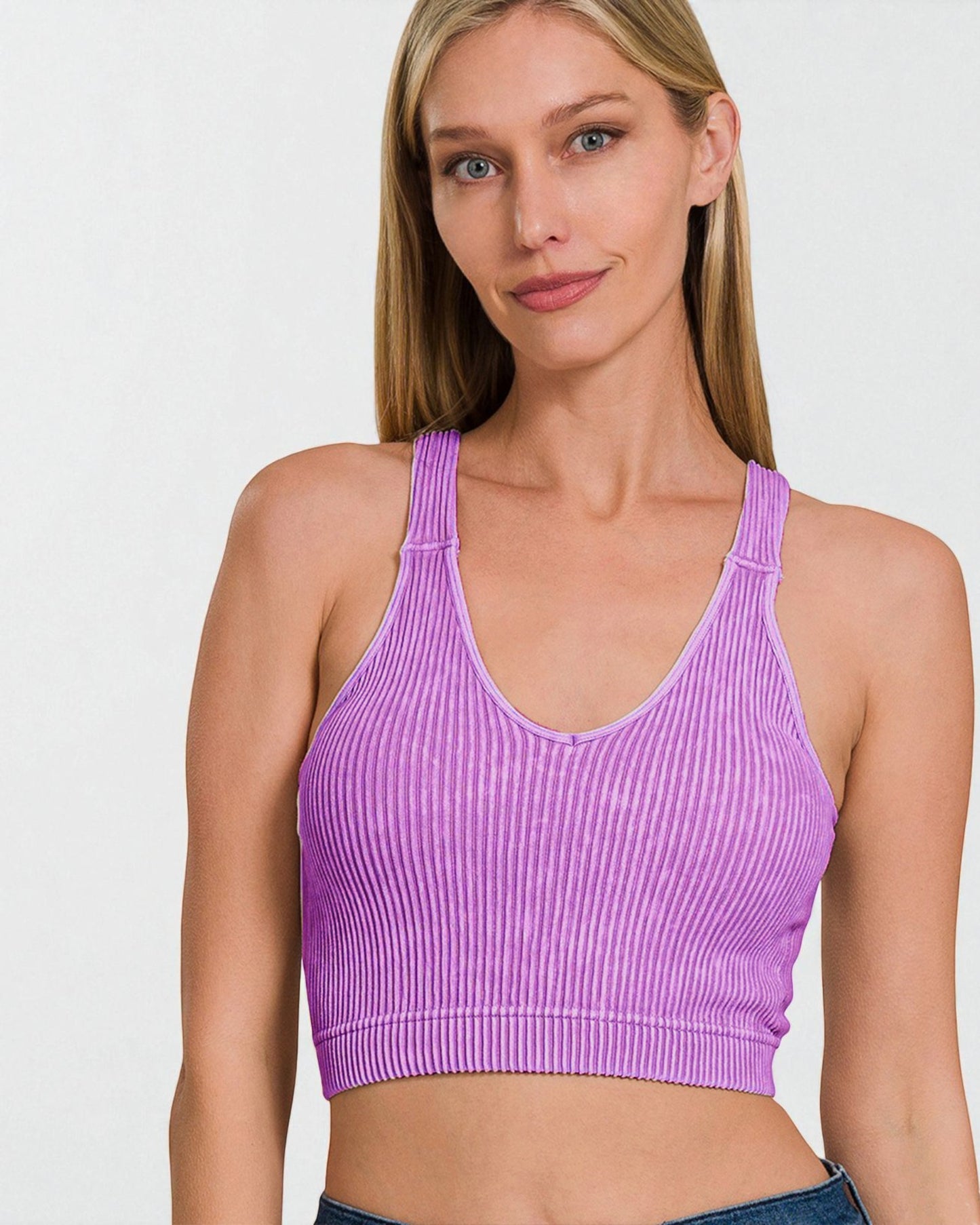 Woman wearing a purple ribbed sports bra against a white background