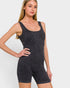 A woman modeling a dark gray ribbed sleeveless short romper against a light gray studio background.
