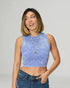 Woman wearing a blue sleeveless top and jeans against a plain background