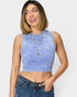 Woman wearing a blue sleeveless top and jeans on a plain background