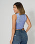 Woman wearing a blue sleeveless top and jeans on a plain background