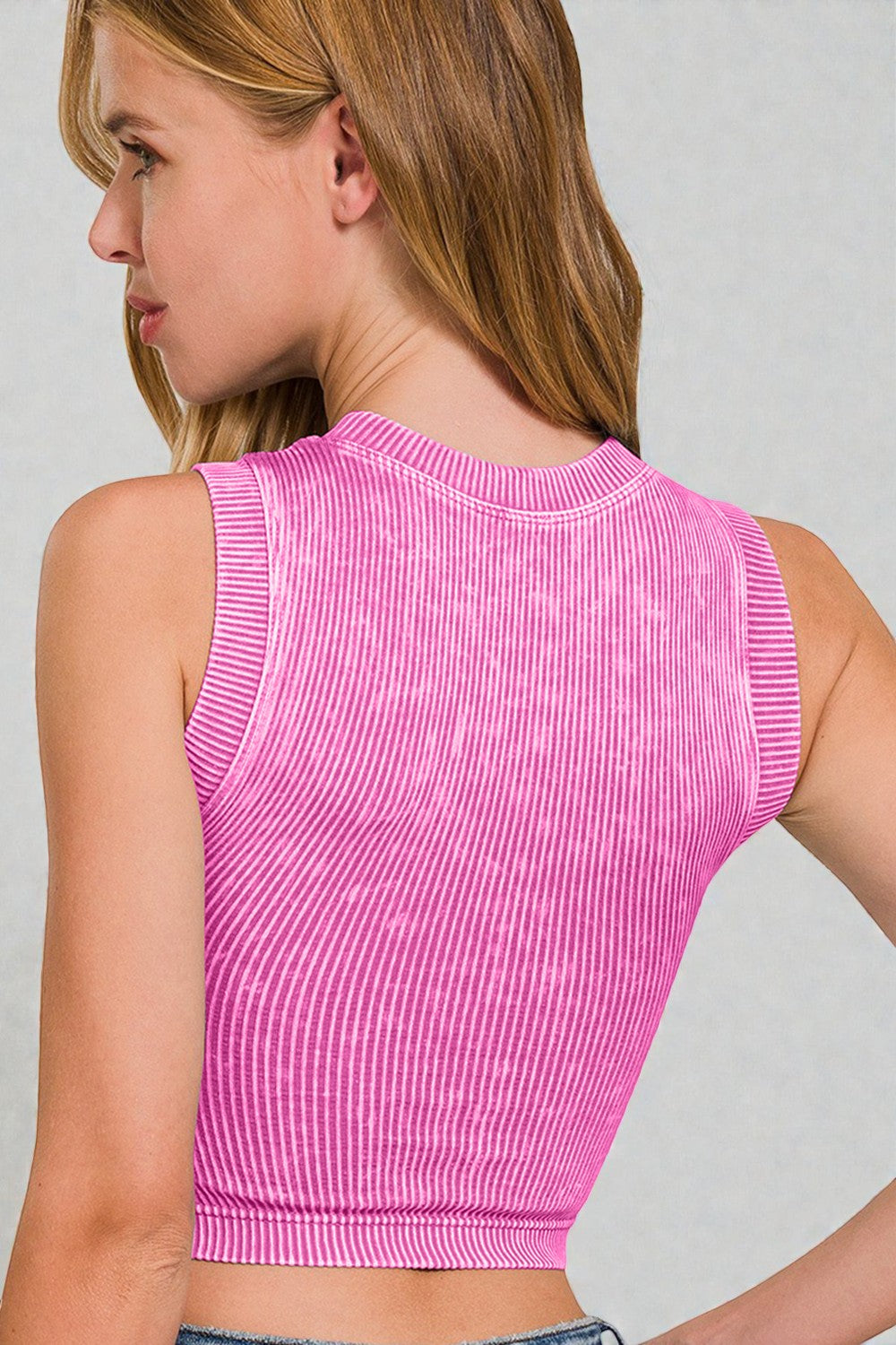Person wearing a pink sleeveless top against a plain background
