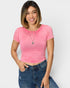 Woman wearing a pink ribbed top and blue jeans on a white background