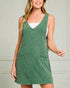 Woman wearing a green sleeveless dress against a neutral background