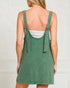 Green denim pinafore dress worn by a person on a plain background