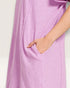 Close-up of a person wearing a light purple dress with a plain background