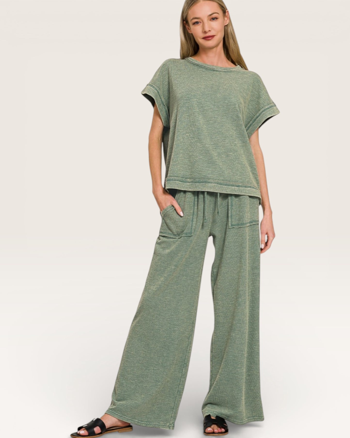 Woman wearing a green outfit with a top and wide-leg pants on a white background