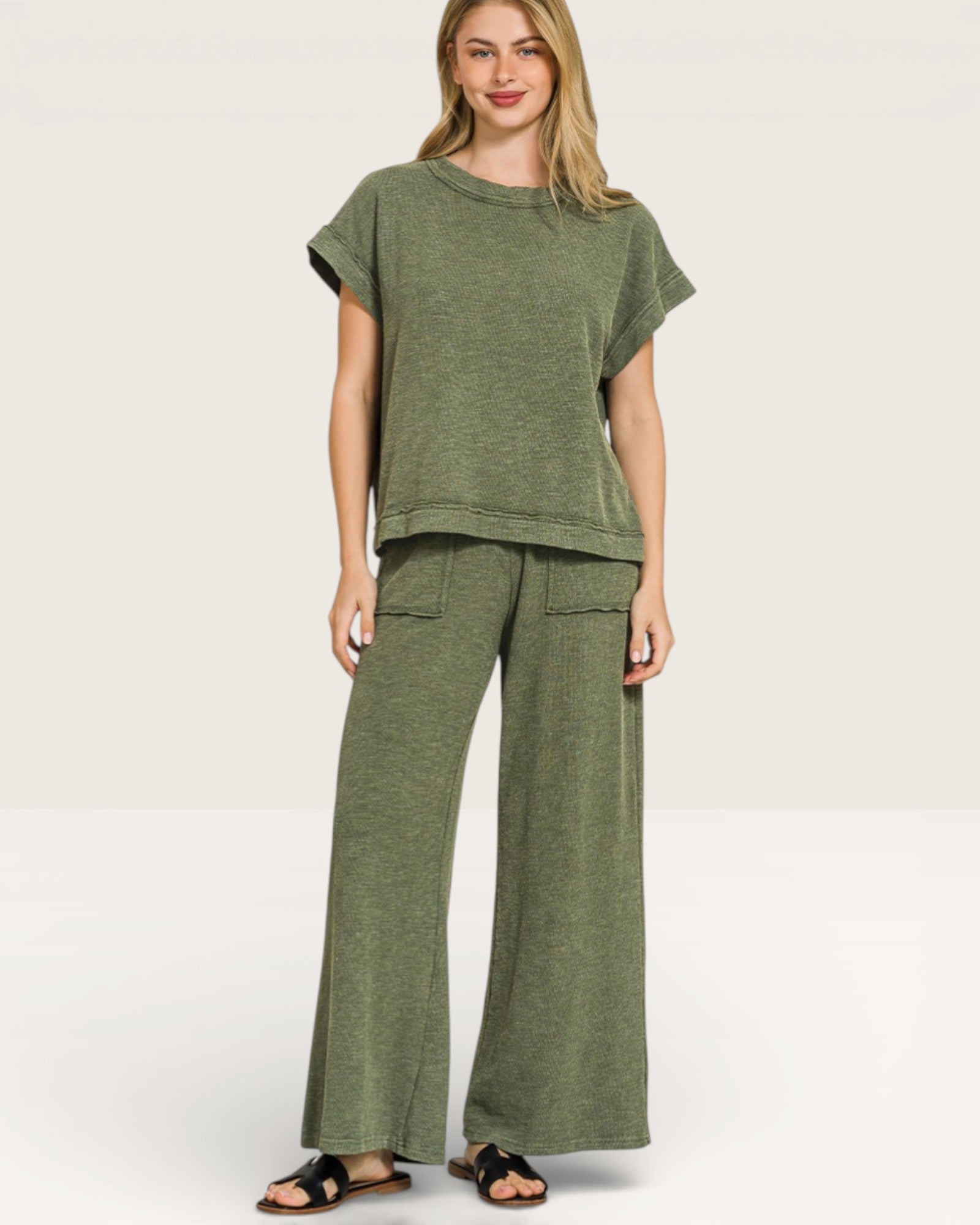 Woman wearing a green outfit with a top and wide-leg pants on a white background