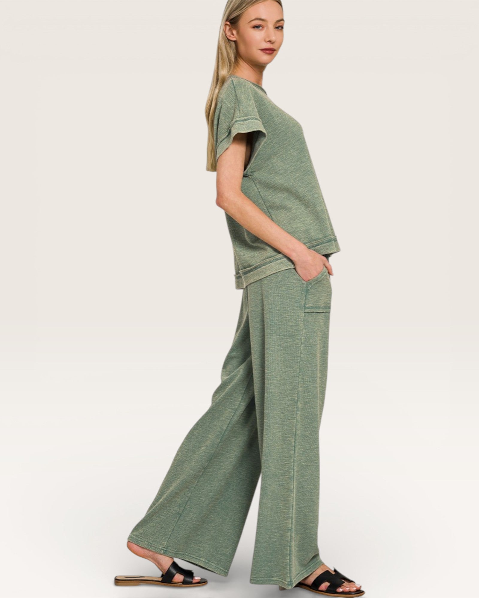 Woman wearing a green outfit with wide-leg pants on a white background