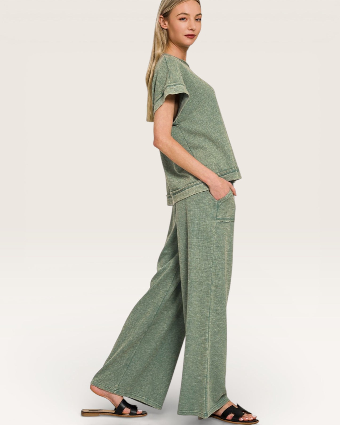 Woman wearing a green outfit with wide-leg pants on a white background